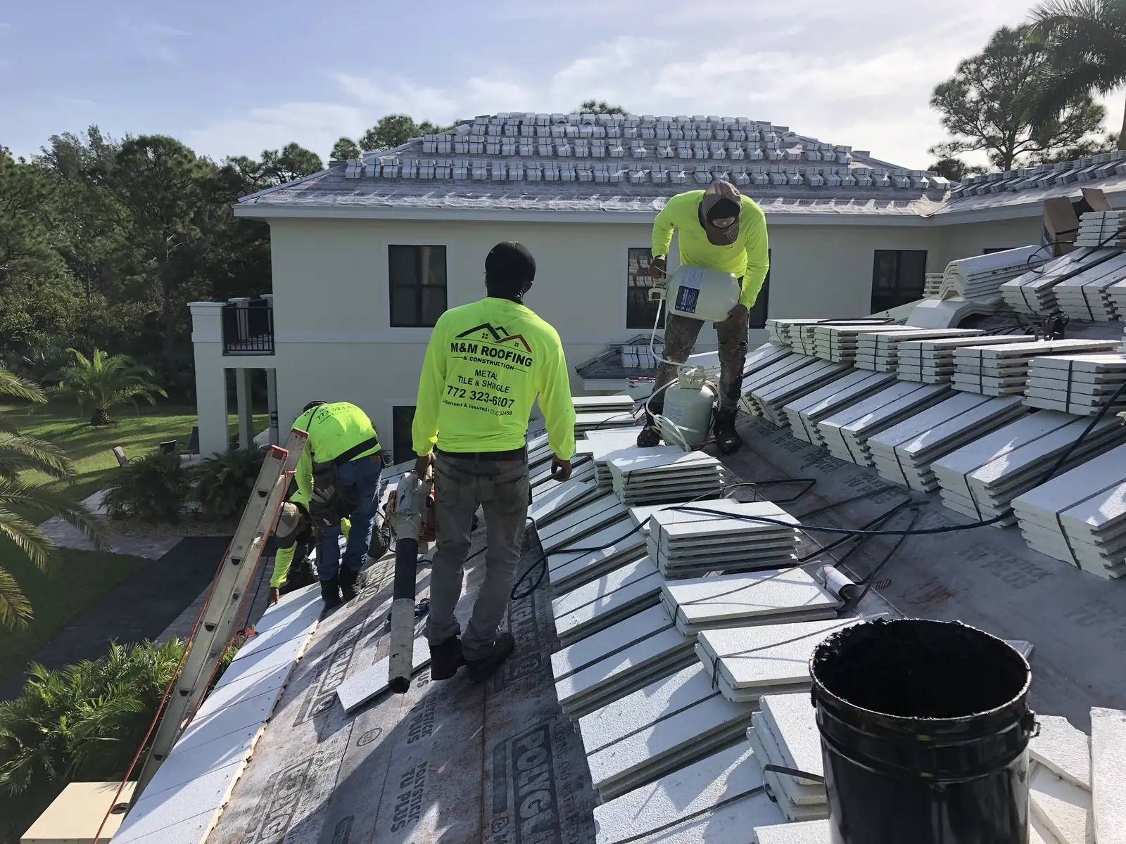 M&M Roofing crew installing metal roof panels on a large two-story home.